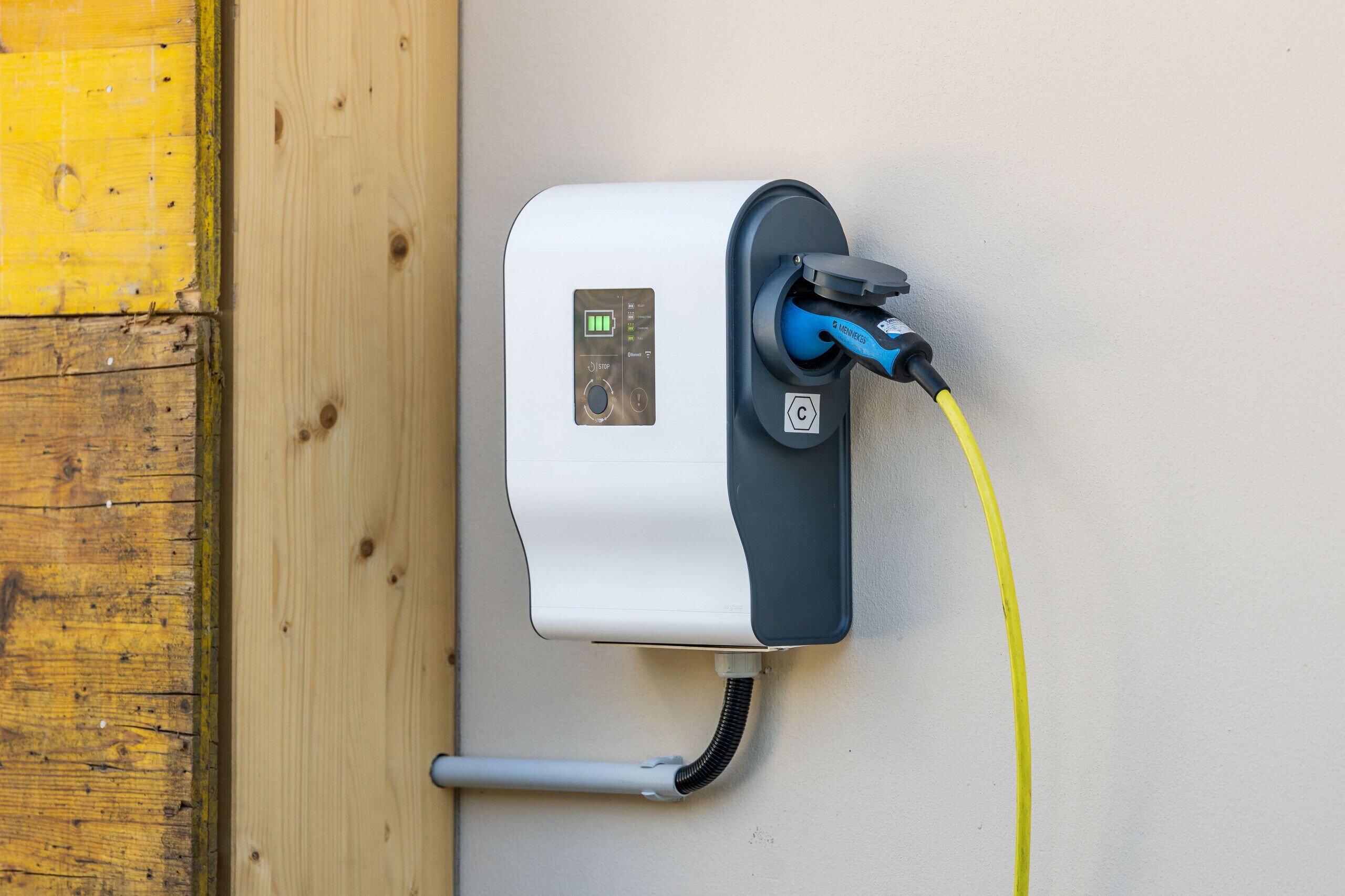 Estació de càrrega per a vehicles elèctrics de muntatge mural, amb pantalla digital, cable de càrrega i sistema de gestió de cables.