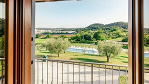 Un balcon offrant une vue sur un paysage verdoyant, avec des arbres et une colline au loin.