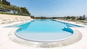 Ein großer, klarer Pool mit kreisrundem Rand und einer umlaufenden Sonnenterrasse.