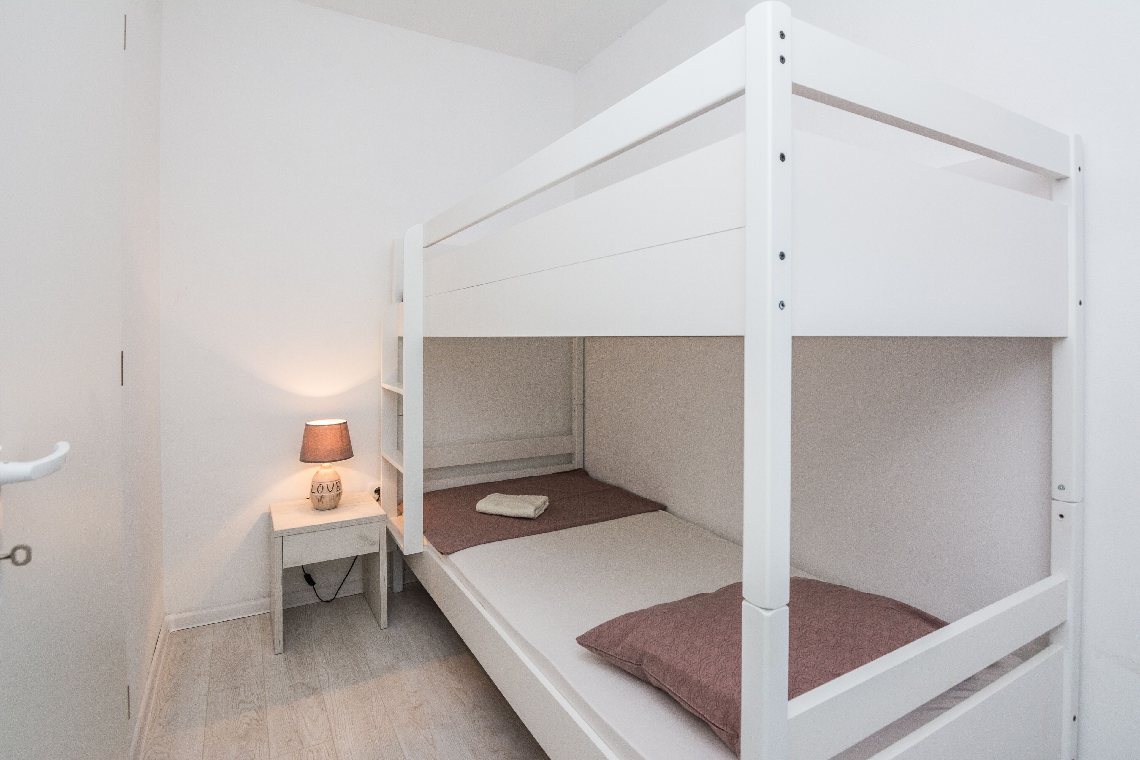 A bunk bed room with a desk and a lamp.