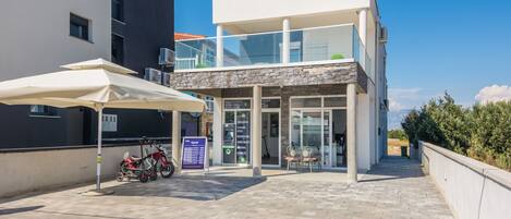 Un edificio moderno con entrada de cristal, una bicicleta estacionada afuera y un cielo despejado.
