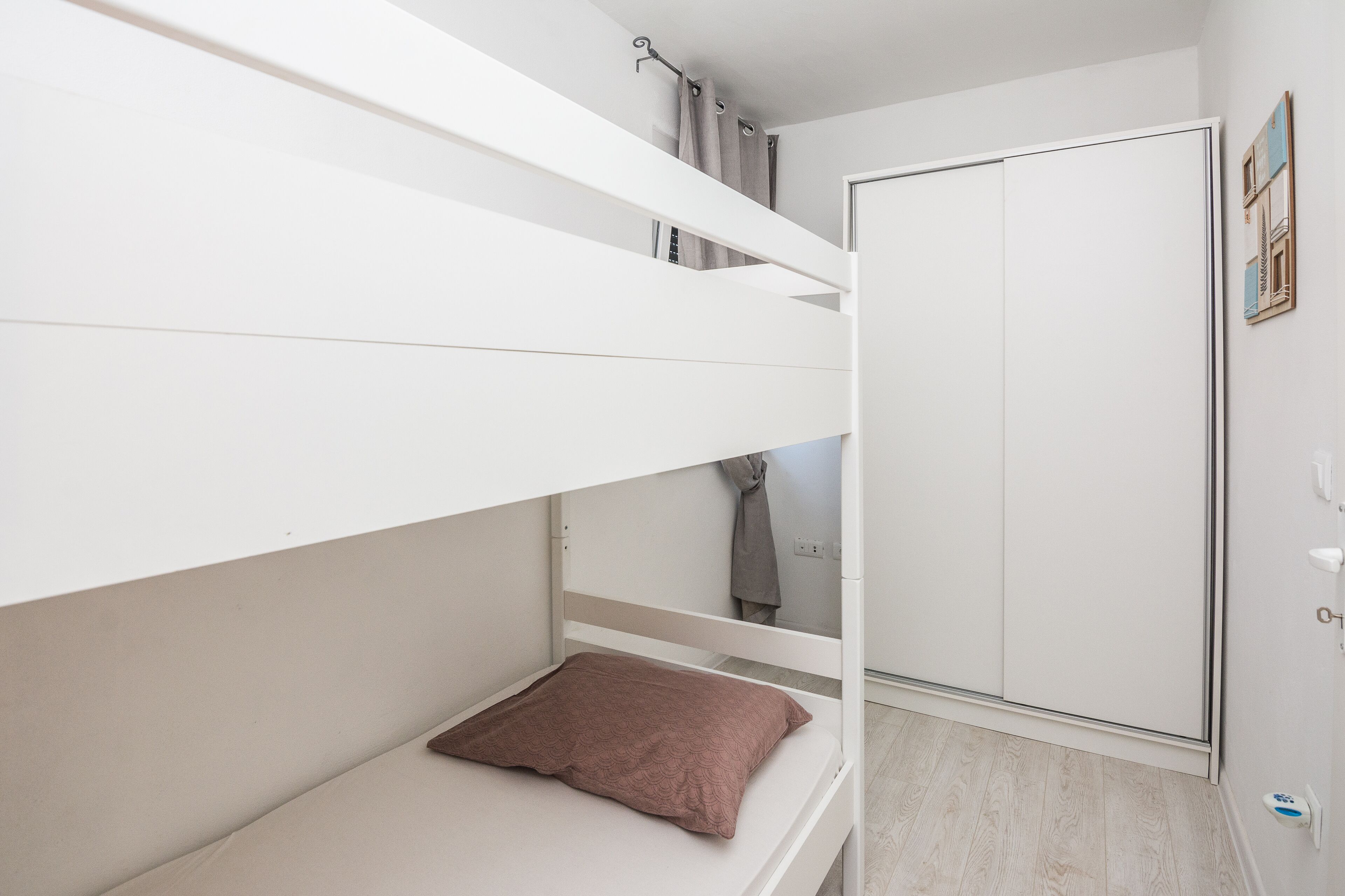 Ein Etagenbett mit einem Bett unten, einem Kleiderschrank und einer Duschkabine.