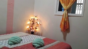 Ein Schlafzimmer mit einem Bett, einer Wandleuchte und einem Fenster mit Vorhängen.