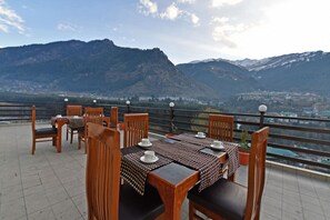 A terrace with tables and chairs, overlooking a mountainous landscape.
