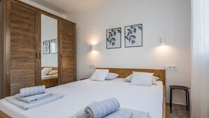 A neatly made bed with two rolled towels, a wooden wardrobe, and two wall-mounted light fixtures. - Apartments Pejakovic (Vir)