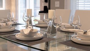 A dining table set with white plates, bowls, and glasses, with a candle centerpiece. - ⭐Modern & Luxurious 4 Bed Home | Gated Resort | SOUTH Facing Pool | Mins to WDW⭐ (Davenport)
