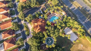 An aerial view of a residential area with a swimming pool, a circular fountain, and a road. - ⭐Modern & Luxurious 4 Bed Home | Gated Resort | SOUTH Facing Pool | Mins to WDW⭐ (Davenport)