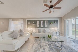 A modern living room with a white sofa, a glass coffee table, and a ceiling fan. - ⭐Modern & Luxurious 4 Bed Home | Gated Resort | SOUTH Facing Pool | Mins to WDW⭐ (Davenport)