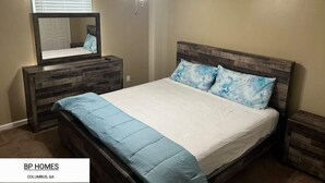 Ein Schlafzimmer mit einem Bett, einem Schminktisch, einem Spiegel und einem Deckenventilator.