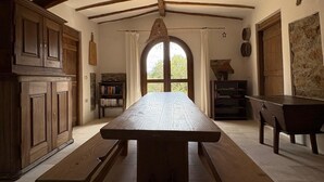 Un interior rústico con vigas de madera a la vista, una mesa de madera en el centro y un ventilador de techo.