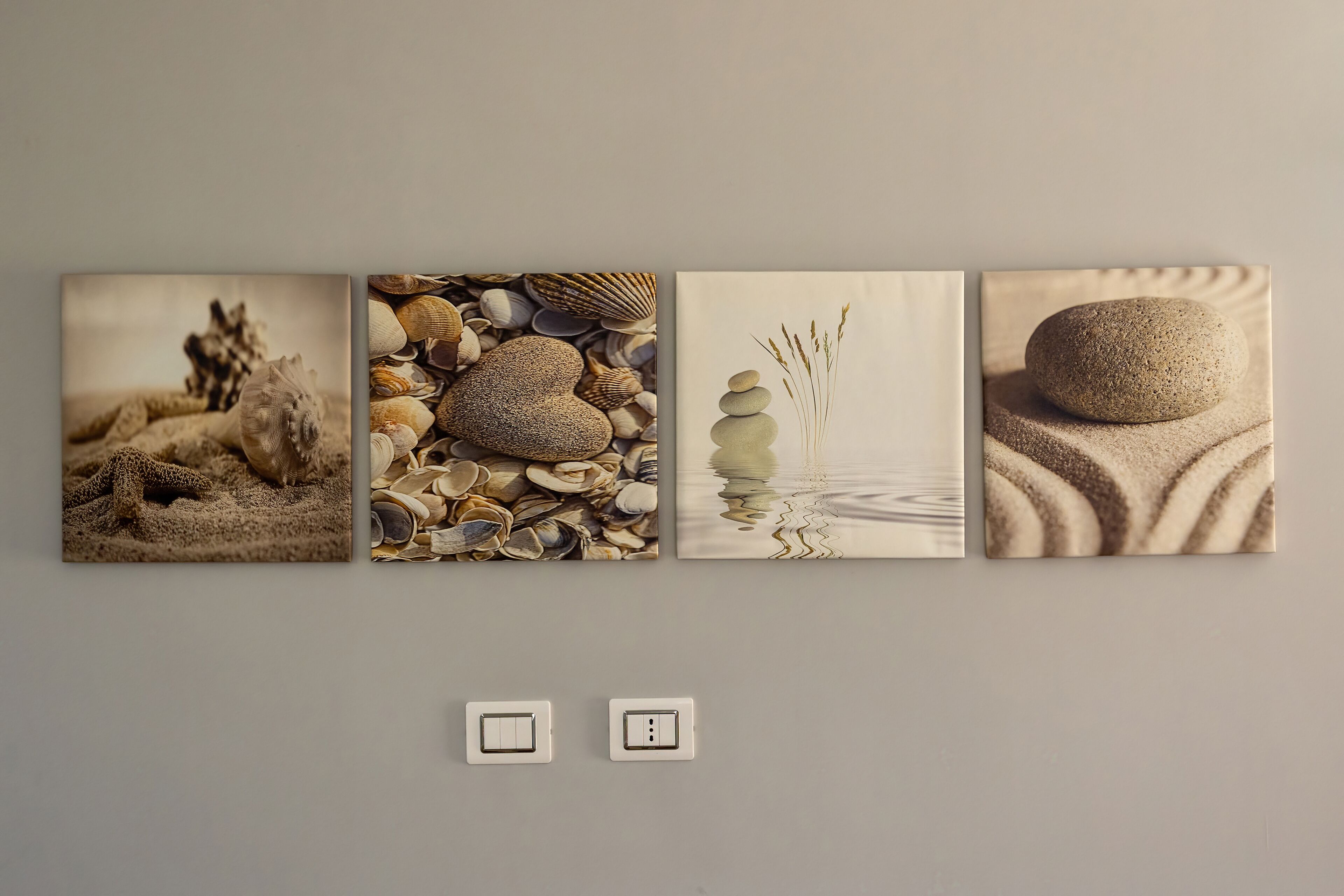A wall with four framed artworks depicting natural scenes.