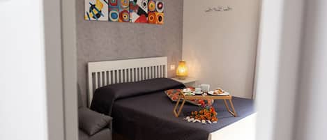 A modern bedroom with a bed, bedside table, lamp, and artwork on the wall.