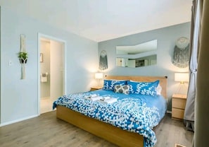 Un dormitorio con una cama grande, mesitas de noche, un espejo y adornos en la pared.