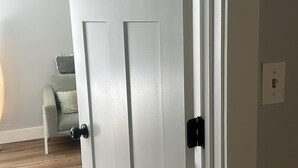 Eine weiße Tür mit modernem Design, einem sichtbaren Lichtschalter und einem Holzboden.
