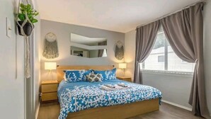 Ein Schlafzimmer mit einem hölzernen Bett, zwei Nachttischlampen, einem Spiegel und einem Fenster mit Vorhängen.