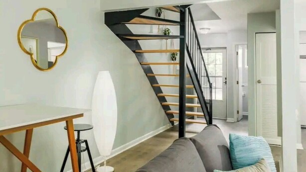 Ein modernes Wohnzimmer mit Treppe, Esstisch und Sofa.
