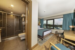 A hotel room with a shower, toilet, bed, desk, and a view of a cityscape. - Csk The Halich Port Istanbul (Istanbul)