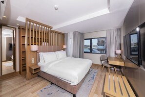 A modern hotel room with a large bed, a desk, a chair, a TV, and a view of the city through the window. - Csk The Halich Port Istanbul (Istanbul)