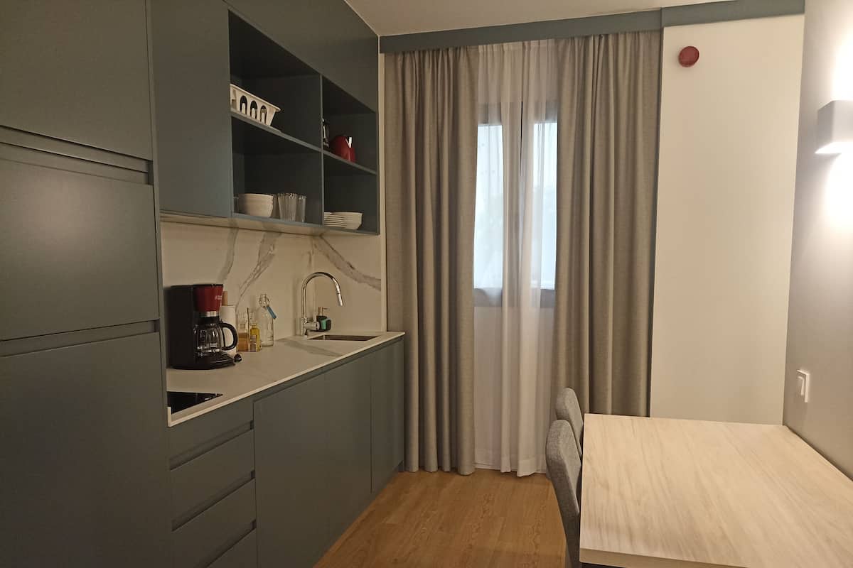 A compact kitchenette with a sink, a coffee maker, and shelves with kitchenware.