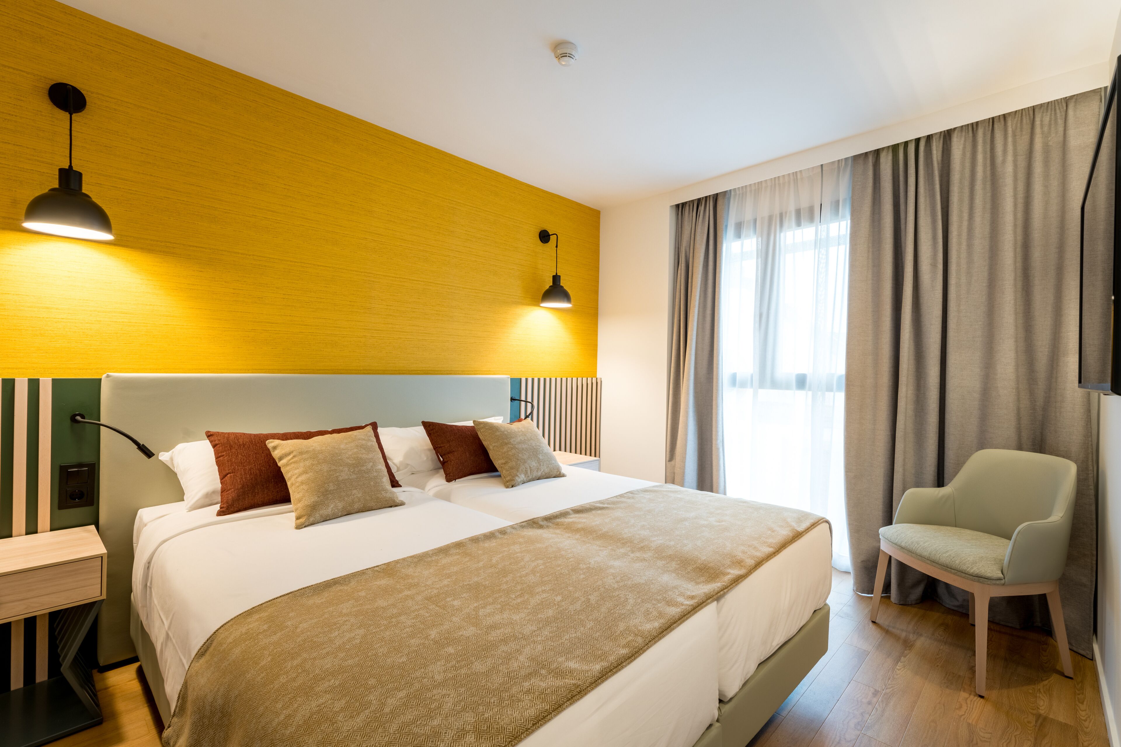 Ein Hotelzimmer mit einem großen Bett, einem Sessel, einem Nachttisch und einer Lampe.