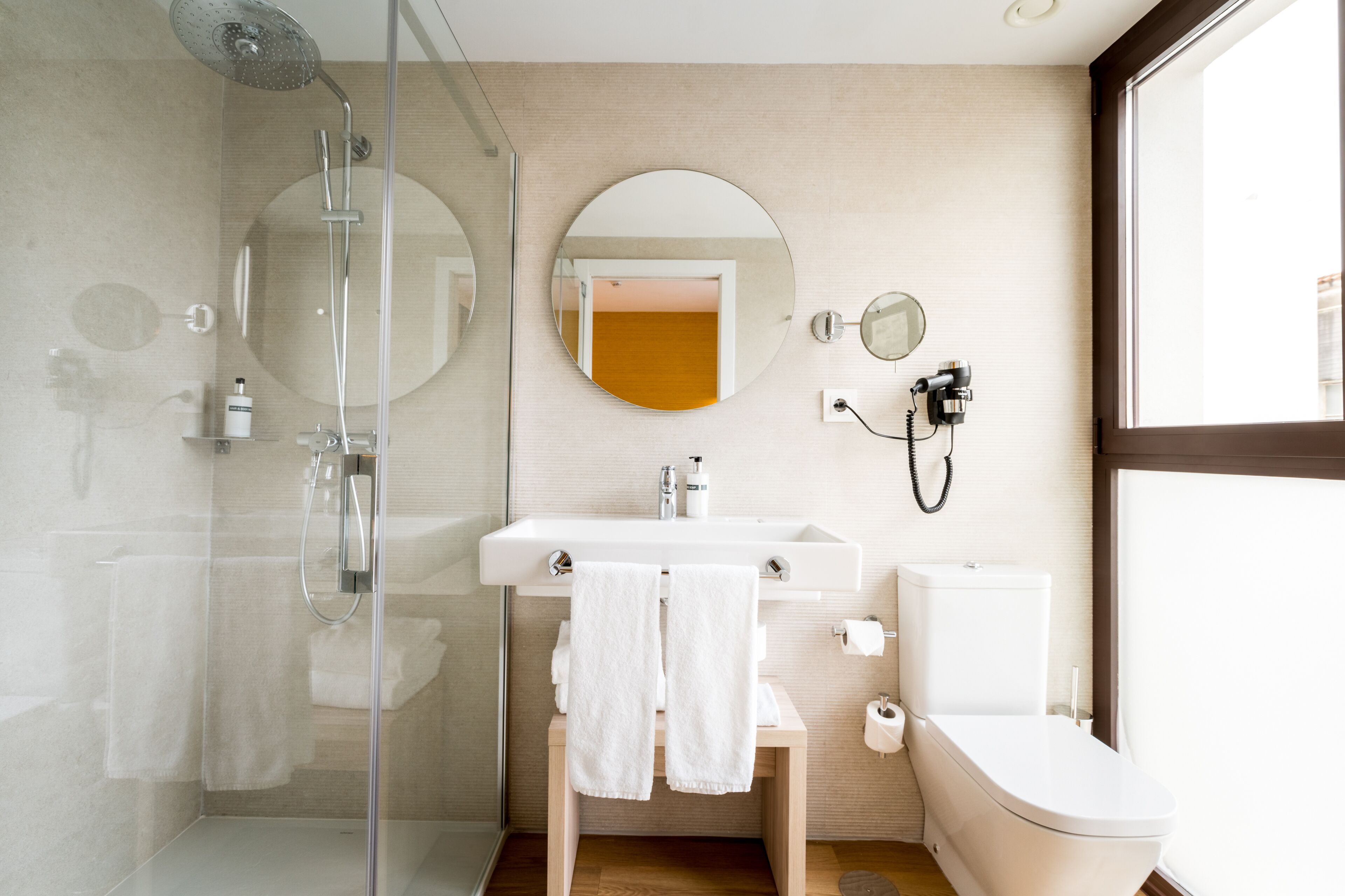 A modern bathroom with a glass shower enclosure, a sink with a mirror, and a toilet.