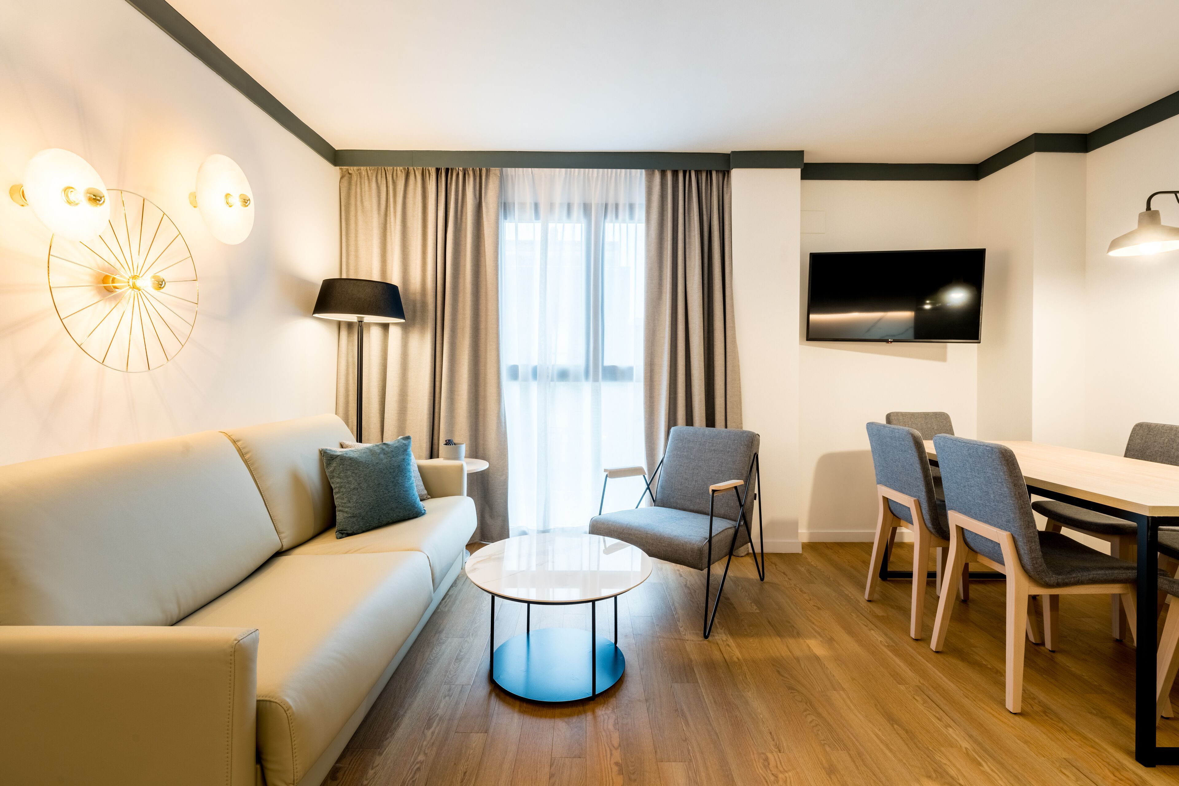 Una sala de estar moderna con un sofá, una mesa redonda de centro y un comedor con sillas y una mesa.