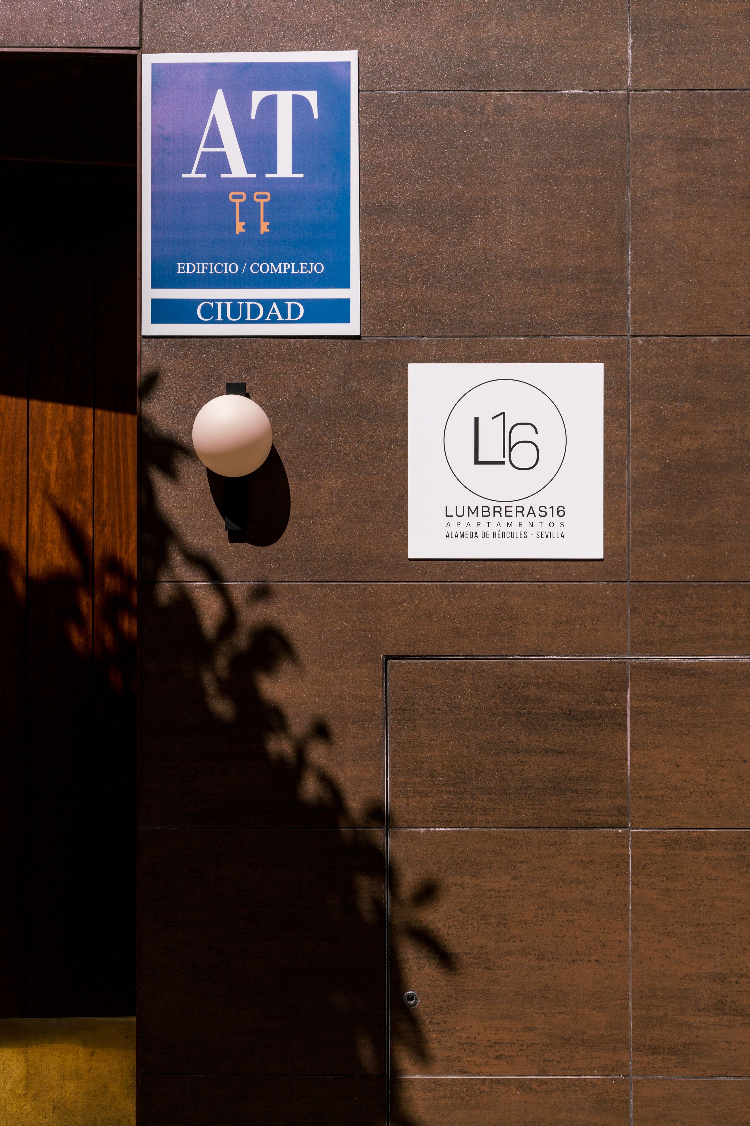 A wall with two signs: one for 'AT Ciudad' and another for 'Lumbreras 16'.
