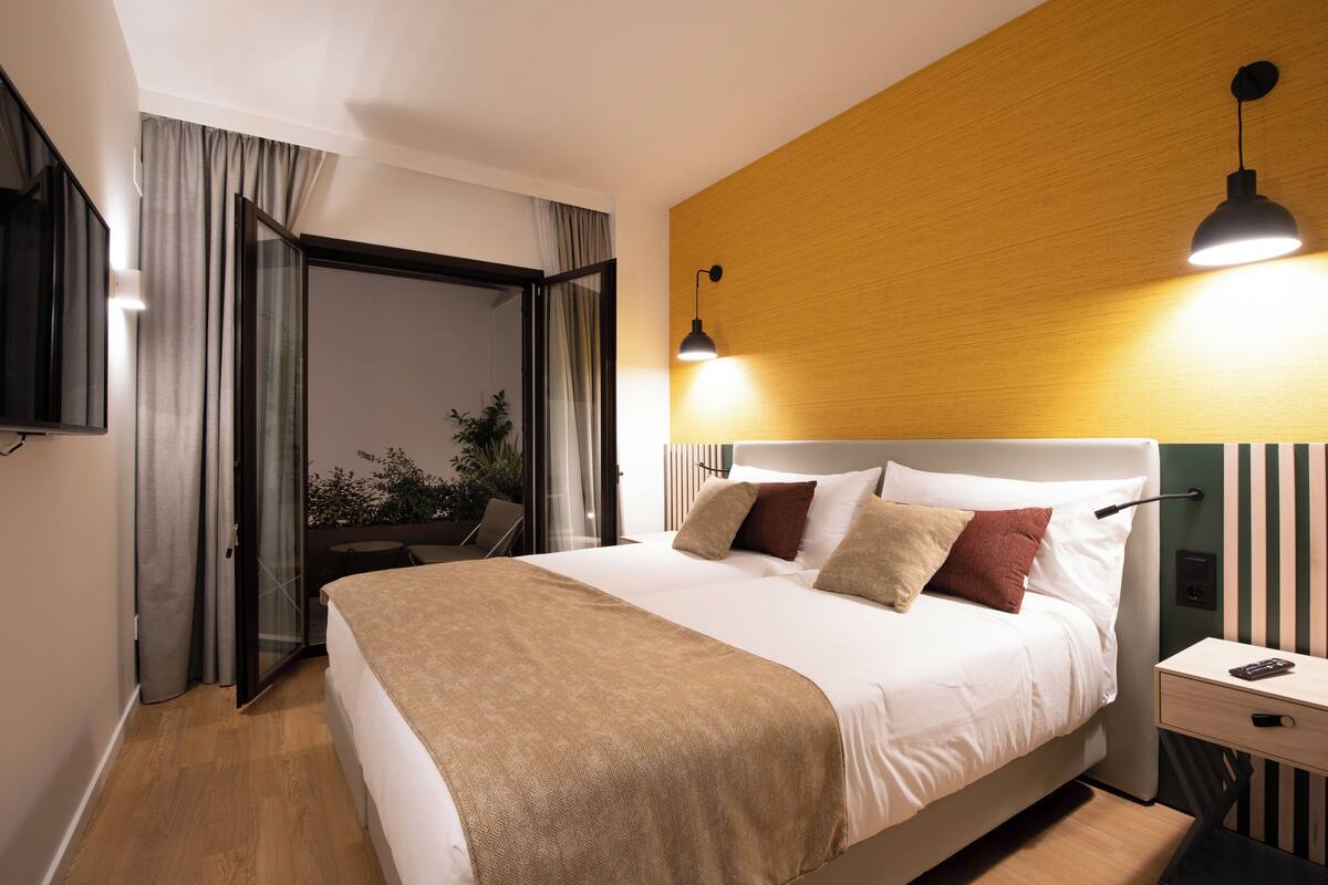 A modern bedroom with a bed, bedside table, and a view of a balcony.