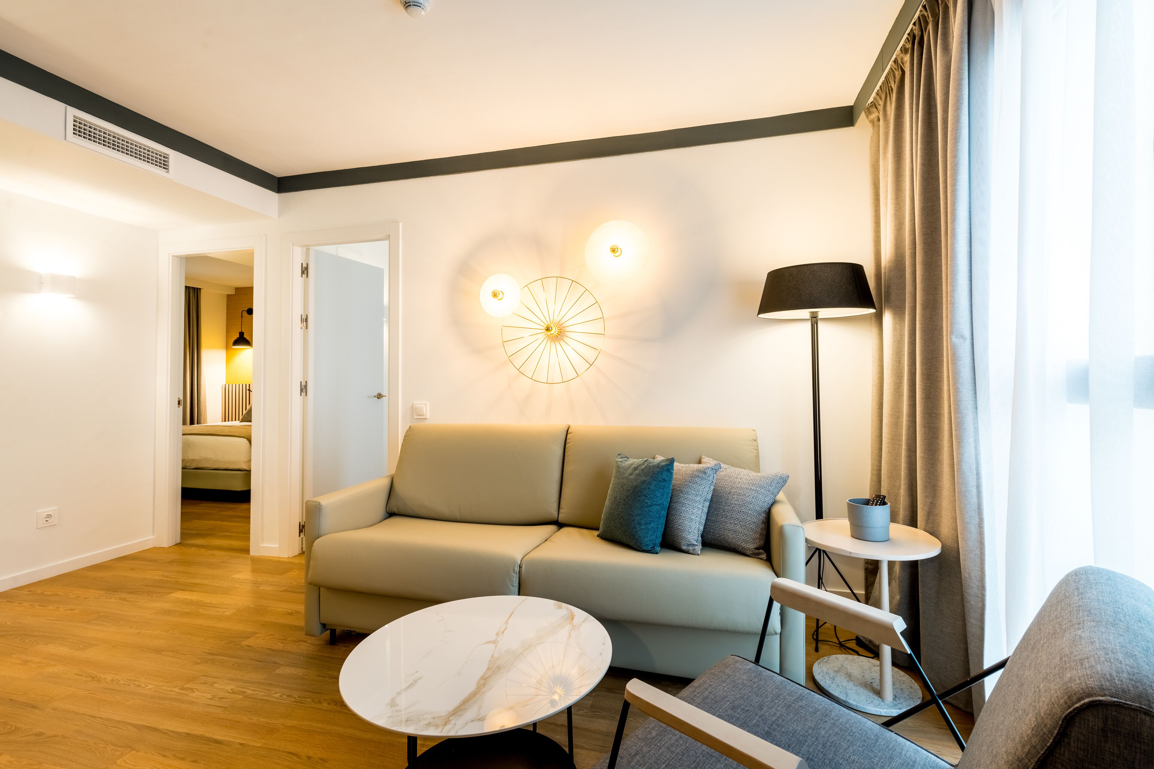 Een moderne woonkamer met een bank, een rond bijzettafeltje en een lamp.