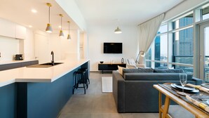Eine moderne Küche mit einer zentralen Kochinsel, Barhocker, einem Essbereich mit Tisch für zwei Personen und einem großen Fenster mit Blick auf die Stadt.