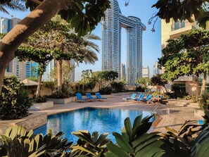 A pool area with lounge chairs and a clear view of tall buildings in the background. - Maison Privee - The Lofts East (Dubai)