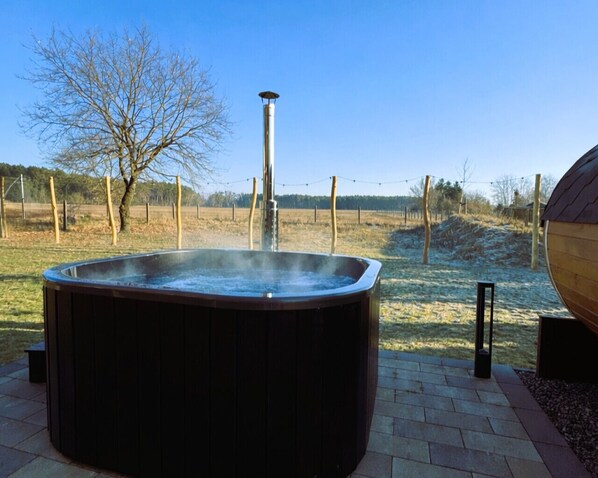 A hot tub in an outdoor setting with a clear sky, surrounded by a wooden deck and a fenced area. - Traumferienvilla am Müritz Nationalpark, Sauna (Rechlin)