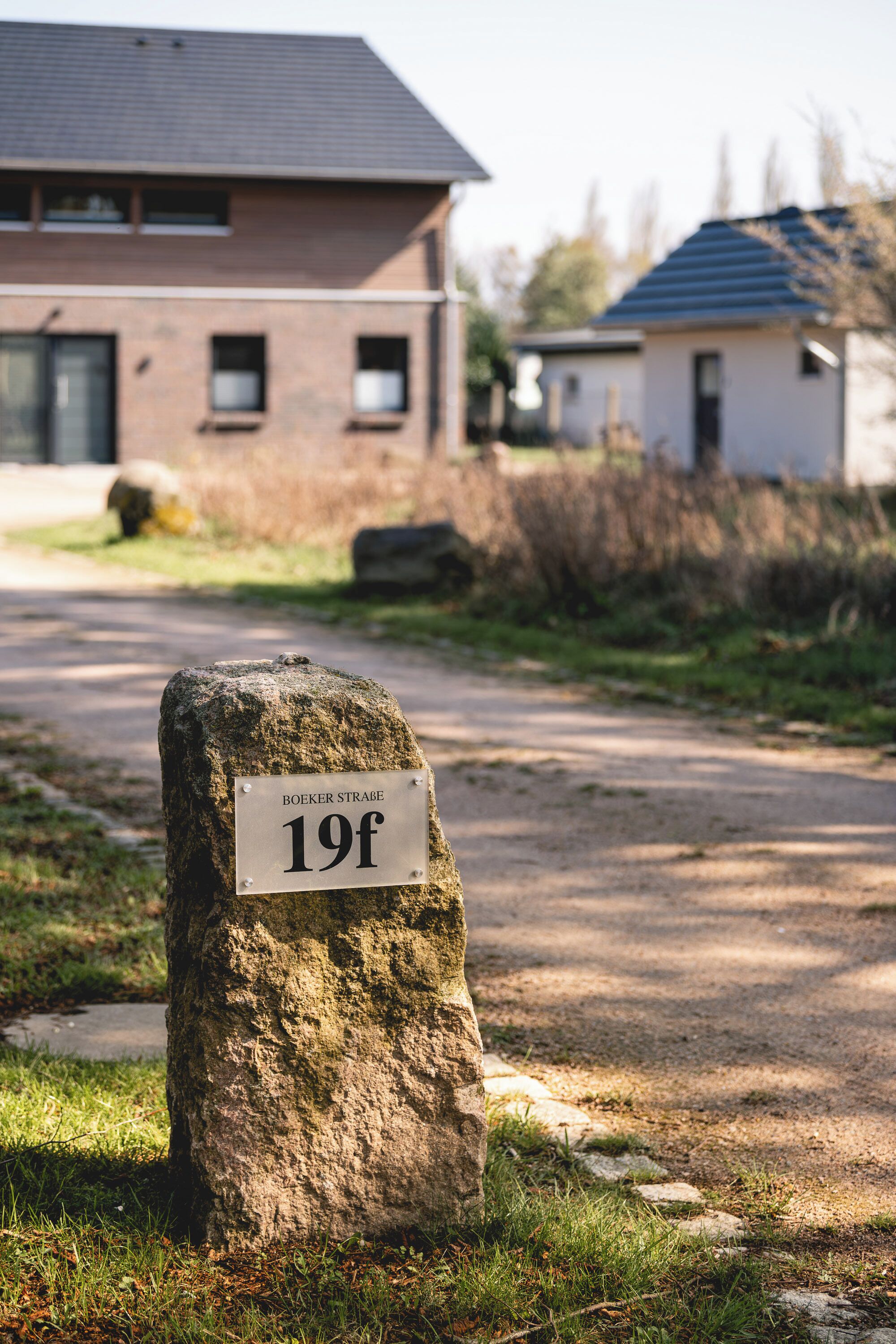 A stone marker with a sign reading 'BOEKER STRAÃE 19f' in a residential area with houses in the background.