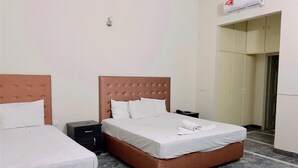 A hotel room with two beds, a marble floor, a wardrobe, and a ceiling-mounted air conditioning unit. - Hotel Rose Inn (Lahore)