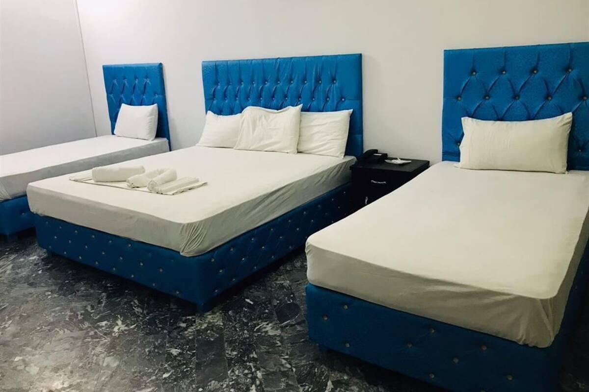 A hotel room with two beds, each with a blue headboard and white bedding.