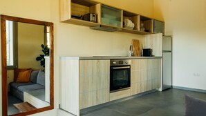 A modern kitchen with built-in appliances, a wooden countertop, and a grey sofa in the adjacent living area.