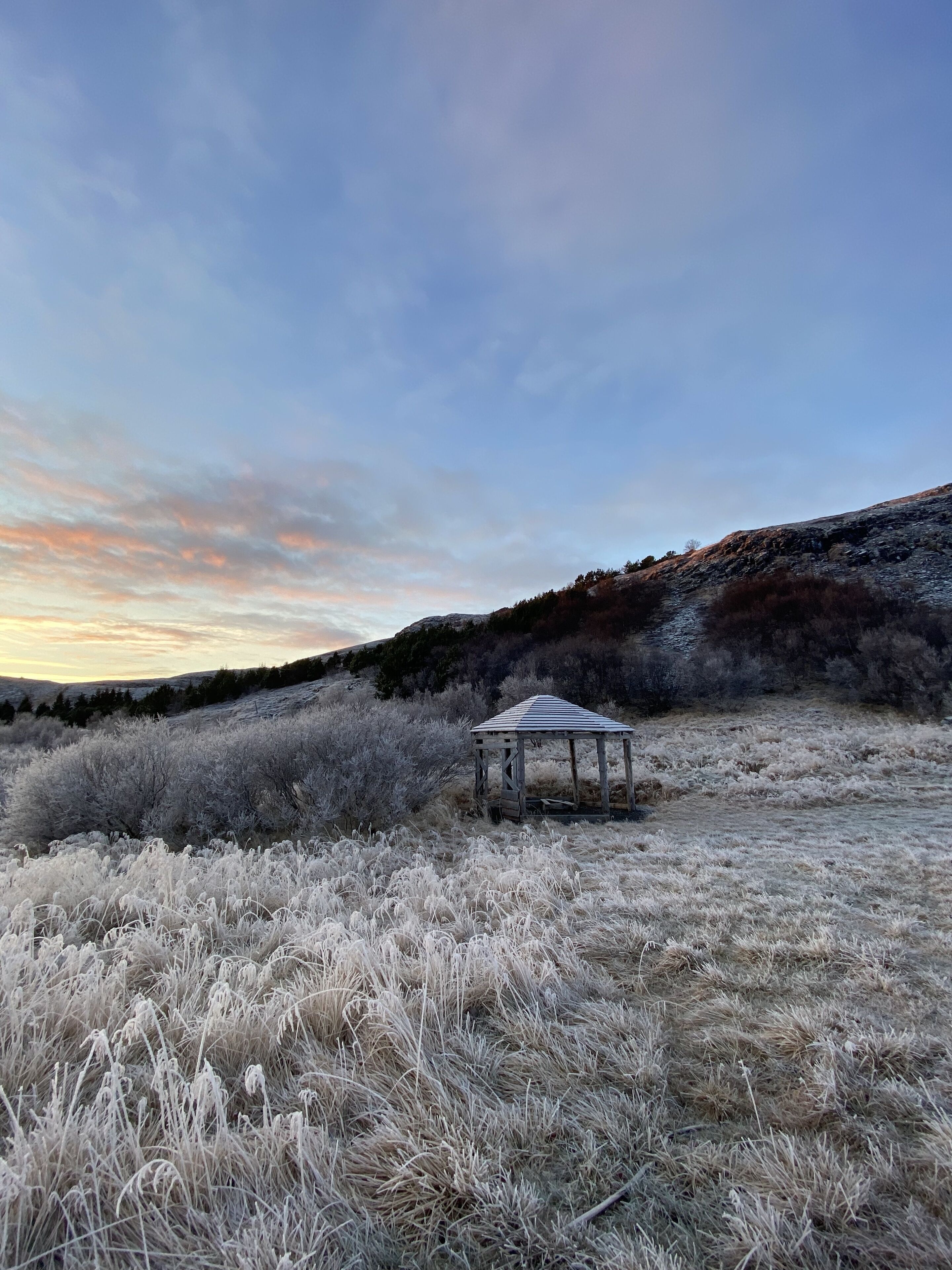 A gazebo in a frosty field with a clear sky.