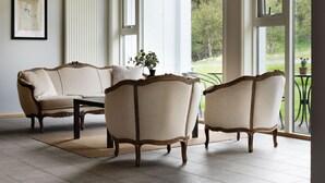 A room with a beige sofa and two armchairs, a small table, and a view of greenery outside. - Dalahótel (Budardalur)
