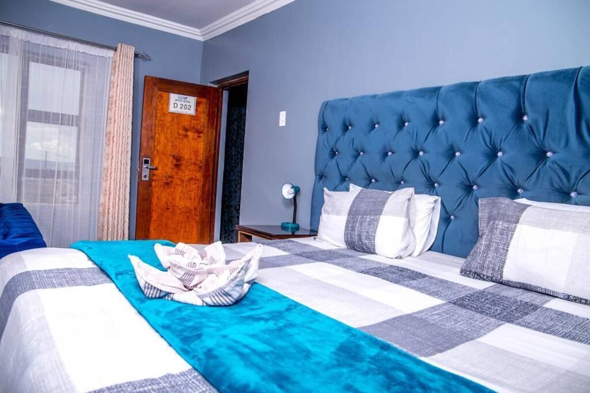 Een hotelkamer met een groot bed, een houten deur en een raam met gordijnen.