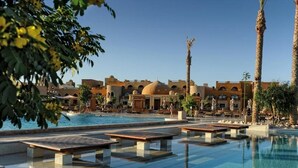 A pool area with clear water, benches, and palm trees. - Makadi Family Star Hotel (Makadi Bay)