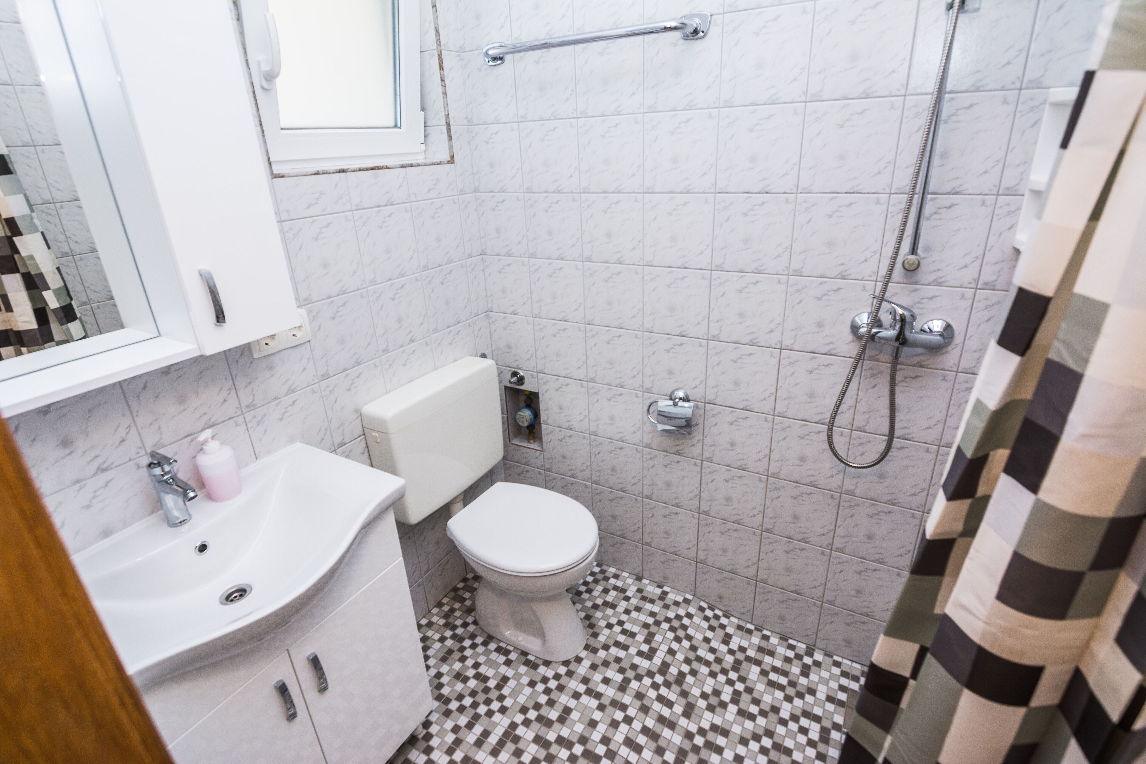Egy fürdőszoba fehér mosdókagylóval, WC-vel és zuhanyzóval.