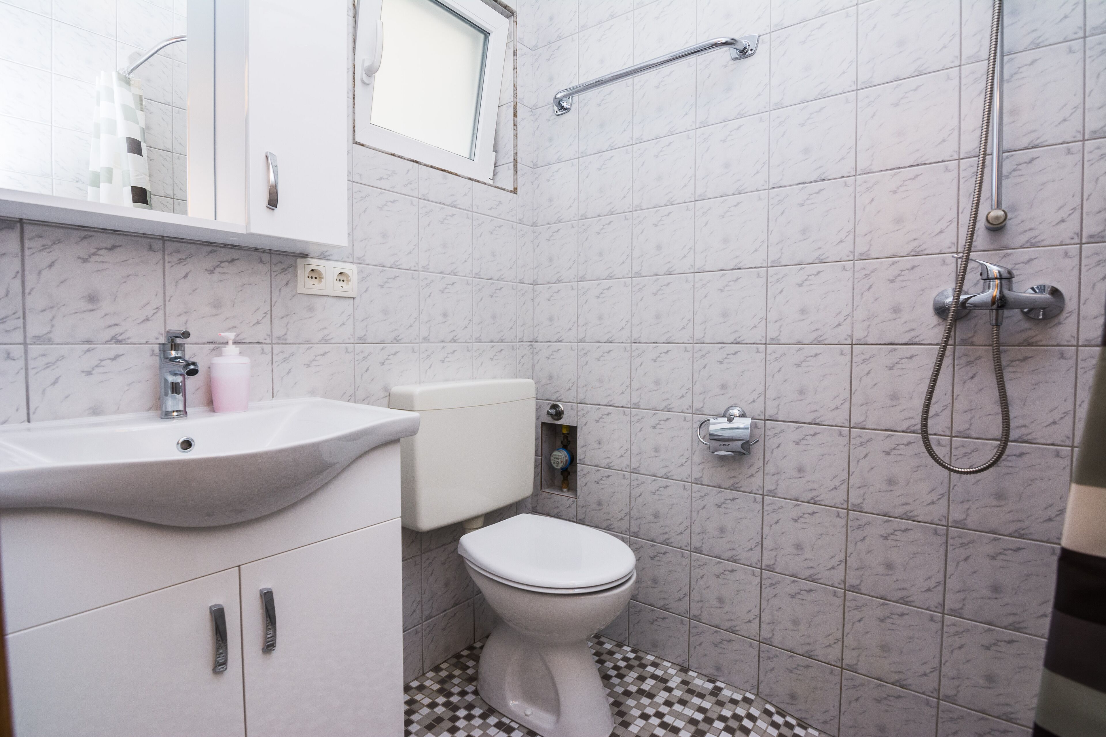 A bathroom with a white toilet, a sink, and a shower.