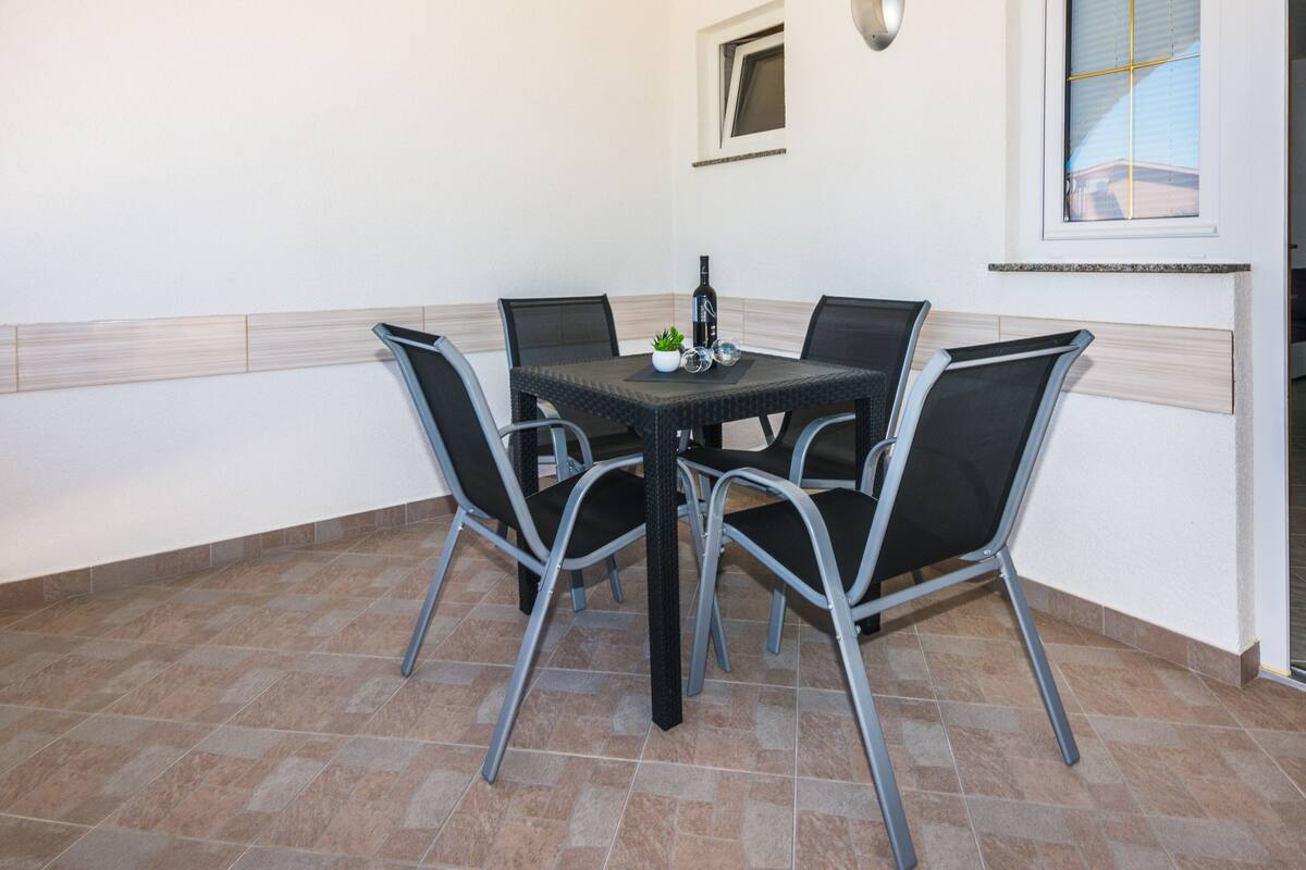 A dining area with a table and chairs, a bottle, and a small plant on the table.