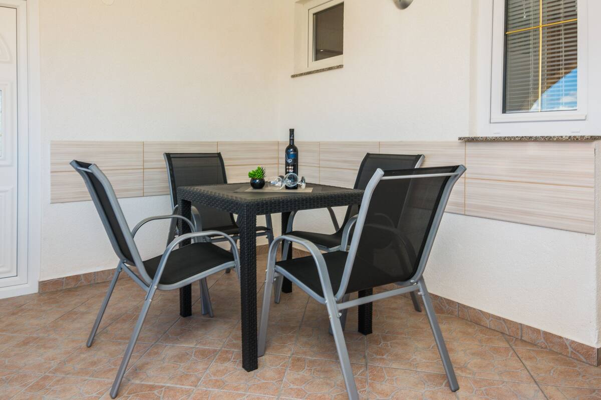 A dining area with a table and four chairs, a bottle, and a small plant on the table.