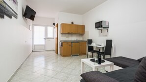Un espacio habitable compacto con kitchenette, zona de comedor y sala de estar.