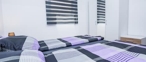 A modern bedroom with a large bed, a wardrobe, and a mirror.