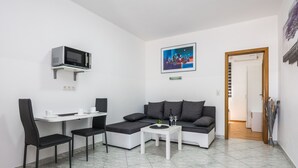 Una sala de estar moderna con un sofá, una mesa de comedor con sillas, un microondas y un cuadro en la pared.