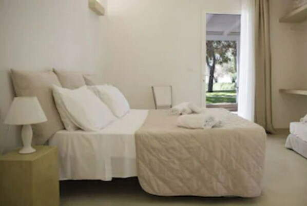 Ein Schlafzimmer mit Bett, Nachttisch und Blick auf einen Garten.