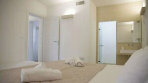 Une chambre d’hôtel comprenant un lit, une salle de bain et une porte donnant sur une autre pièce.