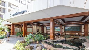 A hotel entrance with a covered outdoor area, a koi pond, and a large painting.